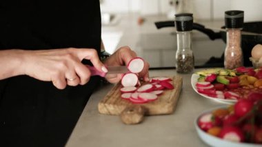 Kadın mutfakta turpları yıkıyor.