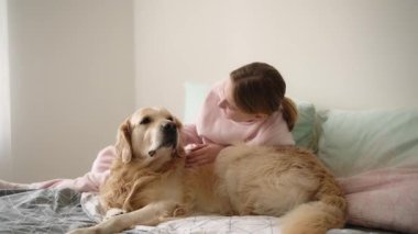 Sevimli küçük kız evde köpek oynatıyor ve onu okşuyor.