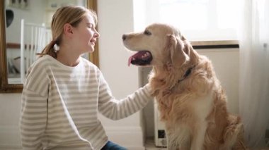 Gülümseyen, mutlu bir genç kız sarılıyor ve evinde sevimli bir köpek besliyor.