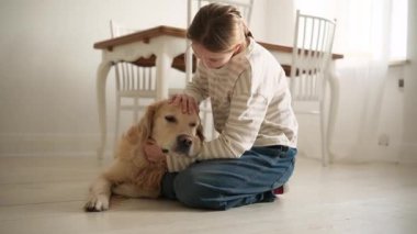 Mutlu genç kız, evinde yerde sevimli bir köpeğe sarılıp okşuyor.