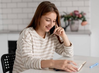 Kız evde telefonla konuşurken gülümsüyor.