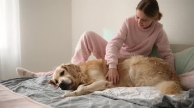 Sevimli küçük kız neşe içinde yatakta güzel bir köpekle oynuyor.
