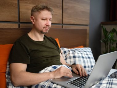 Adam sabahları laptopta haberleri izliyor.