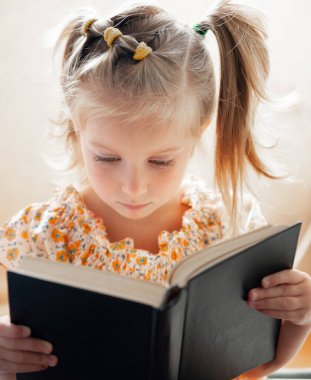 Kitap okuyan tatlı bir kızın yakın plan portresi.