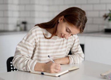 Mutlu kız evde, masada ödevini yapıyor.