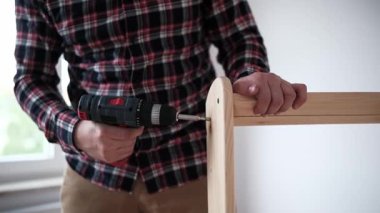 Zanaatkar, parlak bir odada mobilyaları topluyor.