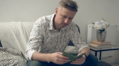 Genç adam pasaportunu evde gezdiriyor ve vizesini kontrol ediyor.