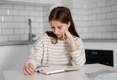 Mutlu kız evde, masada ödevini yapıyor.