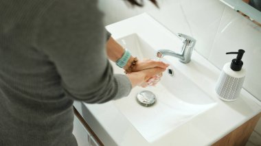 Kadınlar tuvalette ellerini sıvı sabunla yıkıyor, yakın plan.
