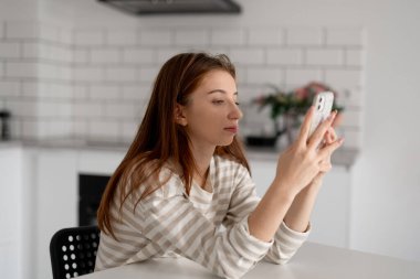 Kız mutlu bir şekilde evde akıllı telefonuyla oynuyor.