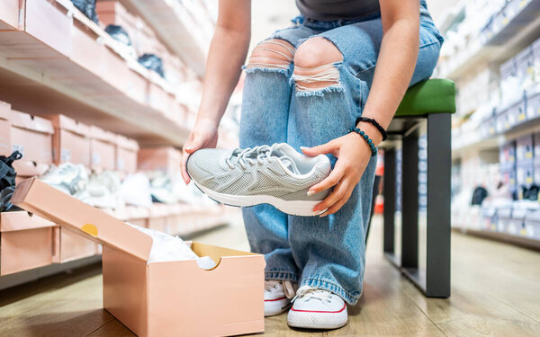 Girl Taking Sneakers Out Of Box In A Shoe Store