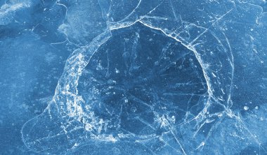 Brittle ice on the surface of a frozen river, close-up natural winter background