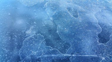 Brittle ice on the surface of a frozen river, close-up natural winter background