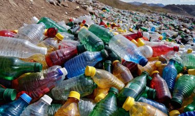 Kullanılmış çok renkli plastik şişeler, çevresel kirlilik, tarlalar ve atık dolu yamaçlar.