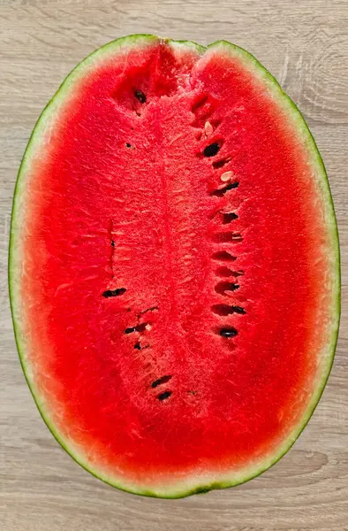 stock image Close-up of cut ripe juicy red watermelon with seeds on a wooden background