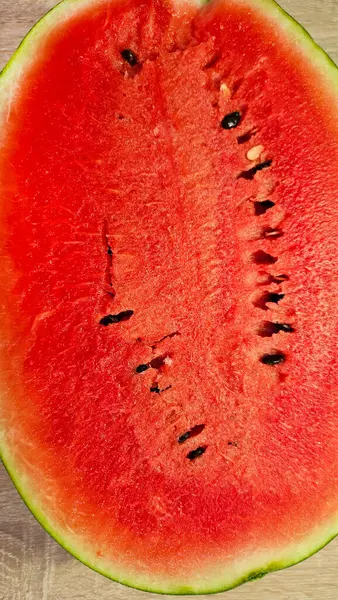 stock image Close-up of cut ripe juicy red watermelon with seeds on a wooden background