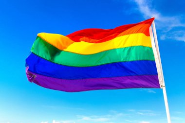 Gökkuşağı LGBT gay bayrağı mavi gökyüzüne karşı dalgalanıyor