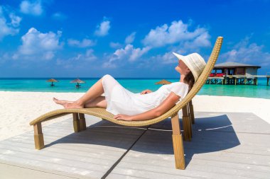 Güneşli bir yaz gününde lüks bir tropik plajda güneşlenen güzel bir kadın.