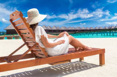 Güneşli bir yaz gününde lüks bir tropik plajda güneşlenen güzel bir kadın.