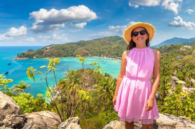 Tayland 'daki Koh Tao adasının panoramik hava manzaralı pembe elbiseli ve hasır şapkalı kadın gezgin.