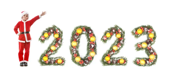 男孩穿得像圣诞老人 2023年的数字是由白色背景的圣诞树树枝做成的 — 图库照片