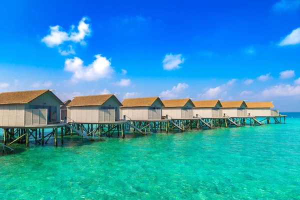 Water Villas (Bungalows) and wooden bridge at Tropical beach in the Maldives at summer day