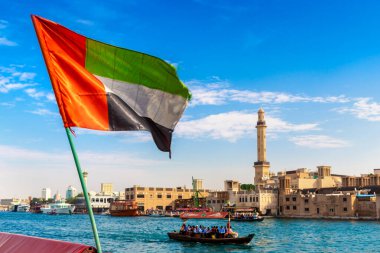DUBAI, BAE - 5 Nisan 2020: Birleşik Arap Emirlikleri bayrağı Abra 'ya karşı - Birleşik Arap Emirlikleri' nin Dubai Körfezi 'ndeki eski geleneksel ahşap tekne