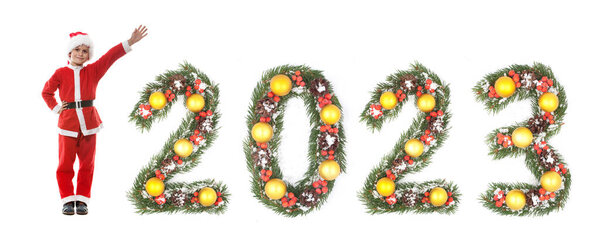 Мальчик одет как Санта-Клаус и 2023 номер, сделанный рождественские ветви елки изолированы на белом фоне
