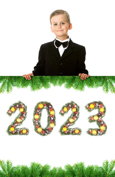 男孩拿着一张圣诞海报和2023年的数字 这些数字是用白色背景隔离开的圣诞树枝制成的 — 图库照片