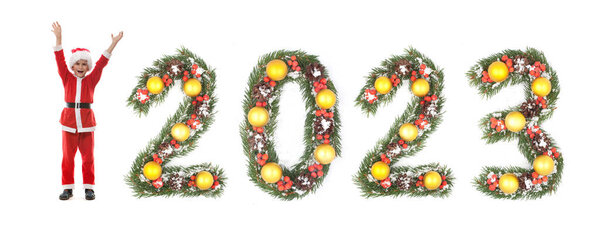 Мальчик одет как Санта-Клаус и 2023 номер, сделанный рождественские ветви елки изолированы на белом фоне