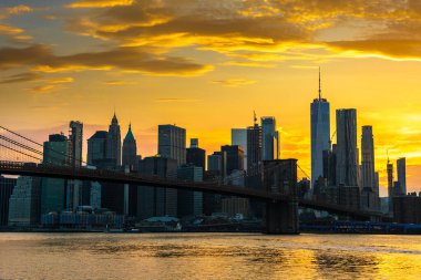 Brooklyn Köprüsü 'nün günbatımı ve New York City, ABD' deki Manhattan şehir merkezinin panoramik manzarası.