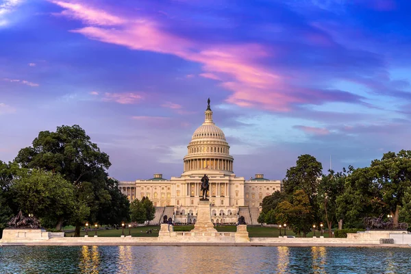 The United States Capitol building and Capitol Reflecting Pool at sunset at night in Washington DC, USA