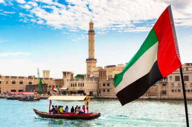 Abra 'ya karşı Birleşik Arap Emirlikleri bayrağına odaklan. Eski ahşap tekne ve Dubai Körfezi' ndeki Dubai Mescidi Camii.