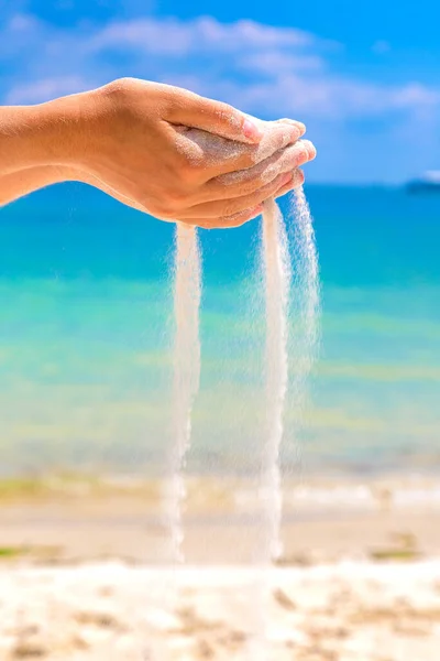White sand falling through woman hands at the tropical beach