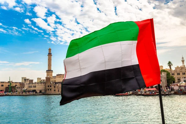 Focus on a flag of   United Arab Emirates flag against  bay Creek and Grand Bur Dubai Masjid Mosque in Dubai, United Arab Emirates
