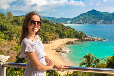 Güneşli bir günde Tayland 'ın Phuket Adası' ndaki Laem Sing plajının panoramik hava manzarasında mavi elbise giyen kadın gezgin.