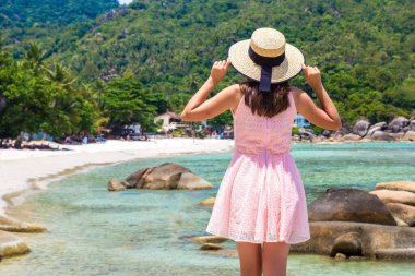 Tayland 'ın Koh Samui adasındaki Silver Beach' te pembe elbise ve hasır şapka giyen kadın gezgin.