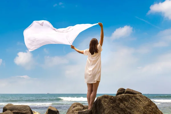 stock image Portriat of Young woman with white cloth fabric fluttering in the wind staying on a tropical beach near sea