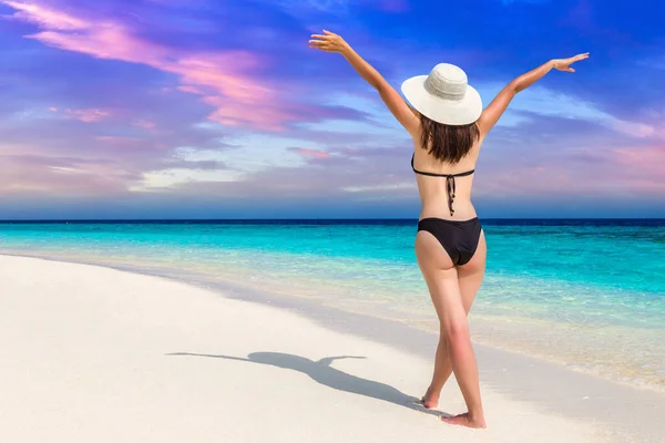 Sexy beautiful woman raising hands up at luxury tropical beach in a sunny summer day
