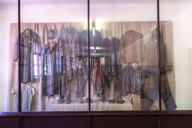 OSWIECIM, POLAND - 7 Eylül 2022: Güneşli bir günde Auschwitz toplama kampında mahkûm kıyafetleriyle sergi, Oswiecim, Polonya