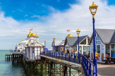 EASTBOURNE, İngiltere - 29 Haziran 2022: Güneşli bir yaz gününde Eastbourne rıhtımı ve plajı, Doğu Sussex, İngiltere