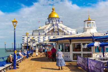 EASTBOURNE, İngiltere - 29 Haziran 2022: Güneşli bir yaz gününde Eastbourne rıhtımı ve plajı, Doğu Sussex, İngiltere