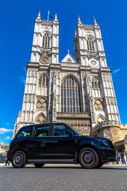 LONDON, İngiltere - 17 Haziran 2022: Londra taksisi (Black Cab) ve Westminster Abbey, İngiltere 'de güneşli bir yaz gününde
