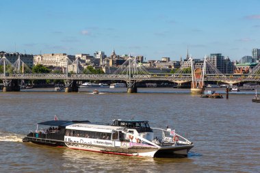 LONDON, İngiltere - 17 Haziran 2022: Thames Nehri 'ndeki Thames Clippers ve Londra' daki Hungerford Köprüsü 'ndeki UBER Teknesi ve İngiltere' deki Golden Jubilee Köprüsü