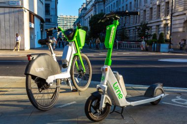 LONDON, İngiltere - 17 Haziran 2022: Güneşli bir yaz gününde Londra 'da bir sokakta modern Lime elektrikli bisiklet ve elektrikli scooter