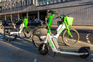 LONDON, İngiltere - 17 Haziran 2022: Güneşli bir yaz gününde Londra 'da bir sokakta modern Lime elektrikli bisiklet ve elektrikli scooter