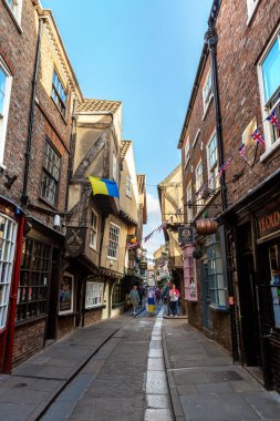 YORK, İngiltere - 10 Haziran 2022: The Shambles - New York 'taki Old Town' da güneşli bir yaz günü Kuzey Yorkshire, İngiltere 'de bir ortaçağ caddesi