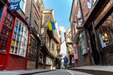 YORK, İngiltere - 10 Haziran 2022: The Shambles - New York 'taki Old Town' da güneşli bir yaz günü Kuzey Yorkshire, İngiltere 'de bir ortaçağ caddesi