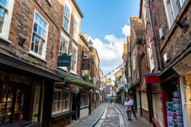 YORK, İngiltere - 10 Haziran 2022: The Shambles - New York 'taki Old Town' da güneşli bir yaz günü Kuzey Yorkshire, İngiltere 'de bir ortaçağ caddesi
