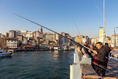 İSTANBUL, TURKEY - 10 Nisan 2022: Güneşli bir günde Türkiye 'nin İstanbul kentindeki Galata köprüsünde balıkçılar
